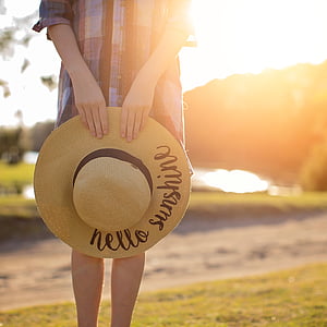person standing in green field holding sun hat thumbnail