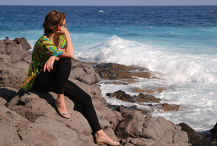 woman wearing green crew neck shirt seating on gray rock during day time thumbnail