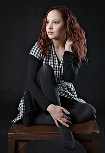 woman wearing black and white checkered dress sitting on brown wooden table thumbnail