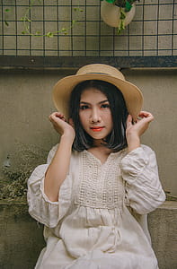 Woman Sitting While Holding Beige Straw Hat thumbnail
