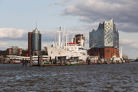 cruise ship beside building under white clouds and blue sky thumbnail