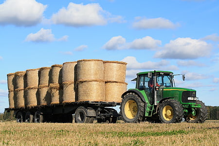 green and yellow John Deere tractor with flatbed trailer carrying brown hays taken at daytime thumbnail