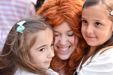 smiling woman embracing two girls thumbnail