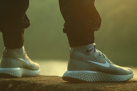 Standing Person Wearing Black Jogger Pants and Gray-and-white Nike React Running Shoes on Concrete Ground thumbnail