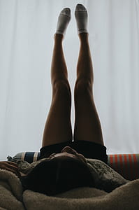 person lying on bed while lifting her feet thumbnail