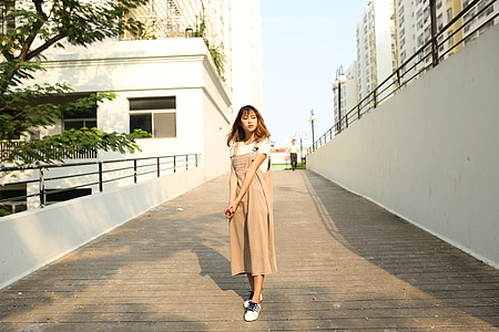 woman standing between white concrete walls near trees thumbnail