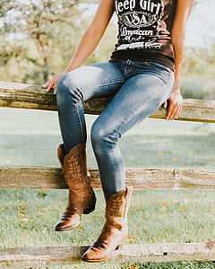 woman wearing brown cowboy boots sitting on brown wooden fence thumbnail
