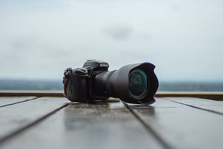 black Nikon DSLR camera on brown surface thumbnail