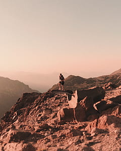person standing on mountain under gray clouds thumbnail