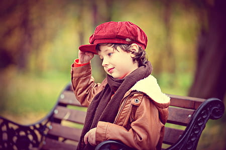 boy sitting on brown metal bench thumbnail