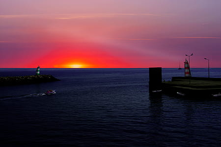 white and red boat on body of water during sun set thumbnail