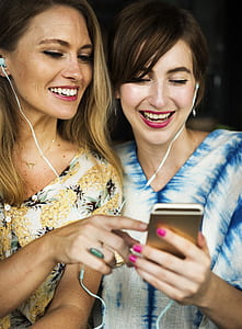 two women wearing white earbuds thumbnail