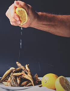 person squeezing lemon on fried fishes thumbnail