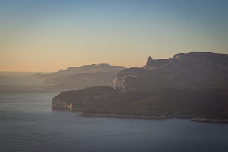 mountain and body of water under white sky thumbnail
