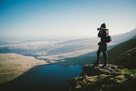 standing man taking photo of water and land thumbnail