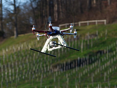 quadcopter drone in mid air near trees thumbnail