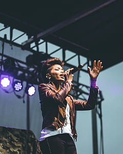 woman in brown leather jacket standing while singing thumbnail