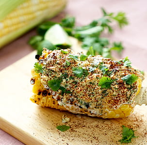 corn with butter, spices, and parsley on beige wooden chopping board thumbnail