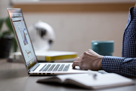 person holding touchpad of laptop computer on top of brown wooden table thumbnail