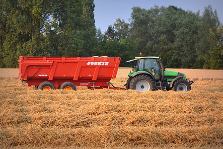 green and black tractor with red trailer on grass field thumbnail
