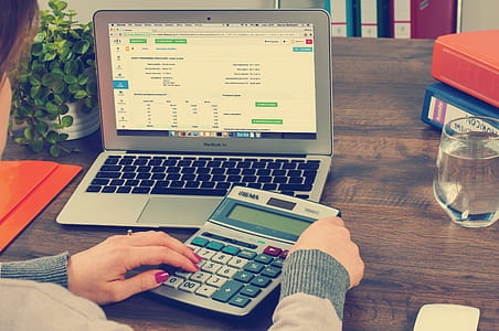 person holding gray calculator on brown wooden tabletop thumbnail
