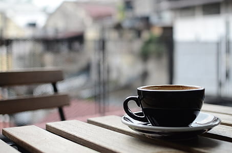 black ceramic mug and white ceramic saucer on brown wooden table thumbnail