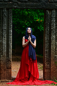 man in red long dress standing between gate thumbnail