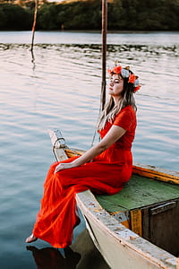 woman in red dress sitting on white wooden boat during daytime thumbnail