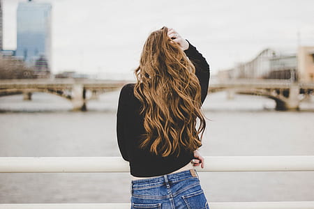 woman standing near metal railing facing body of water thumbnail
