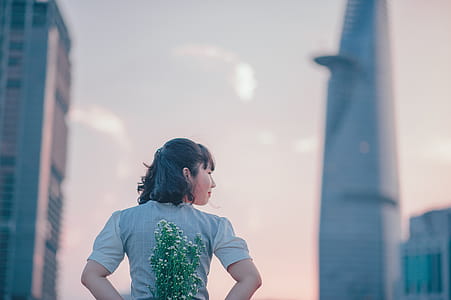 photo of Woman in Gray Top Holding Flowers on Her Back thumbnail