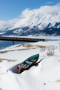 brown and blue boat on snow near the body of water during daytime thumbnail