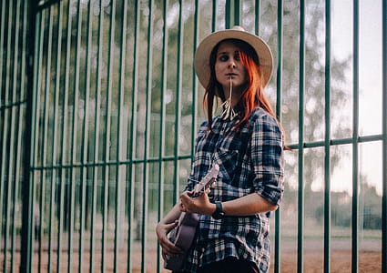 Woman Standing Near Green Fence While Playing Guitar thumbnail