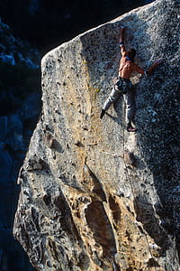 topless man climbing gray rock mountain during daytime thumbnail