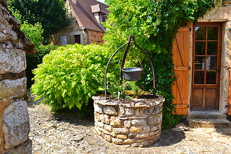 gray and brown water well beside house during daytime thumbnail