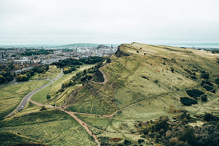 Green hill by growing city and curvy roads thumbnail