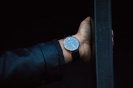 person wearing black suit blazer and round analog watch at 5:28 while holding a post thumbnail