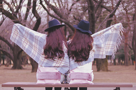 two woman wearing blue and white scarves sitting on bench thumbnail