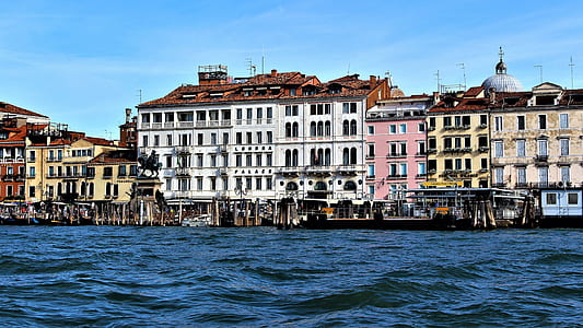 white and beige concrete house near body of water thumbnail