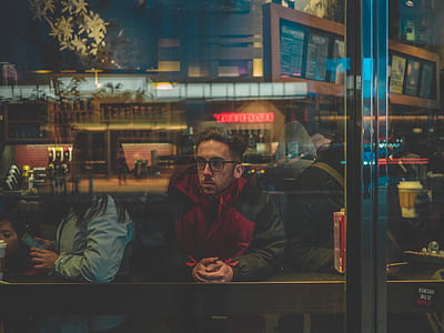 man in red and black jacket sitting on chair inside the room thumbnail
