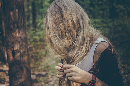 woman braiding hair beside tree thumbnail