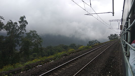 empty railroad tracks near green grass hill thumbnail