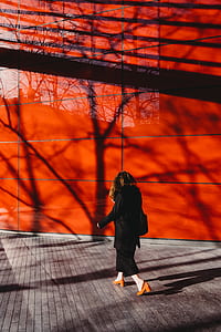 woman walking beside red wall thumbnail