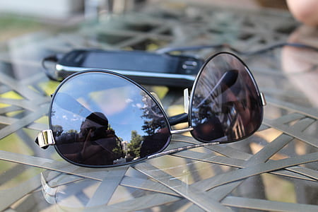 black aviator sunglasses with black frames beside smartphone thumbnail