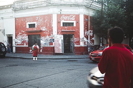 man walking on road street near red car at daytime thumbnail
