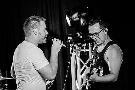 grayscale photography of two men singing and playing guitar thumbnail