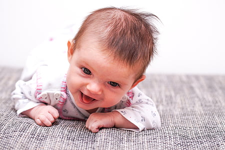 baby laughing while crawling on gray mat thumbnail