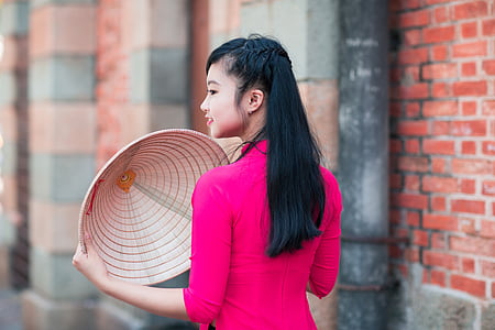 woman wearing pink 3/4-sleeved top holding brown hat thumbnail