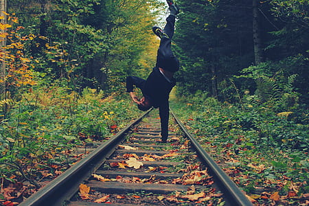 Man Standing With His Right Hand on the Train Rails in Middle of Forest thumbnail