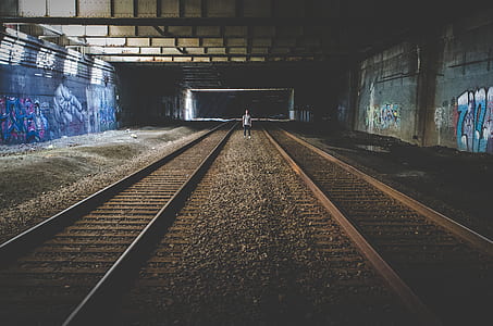 filtered photography of person standing in the middle of train railways thumbnail