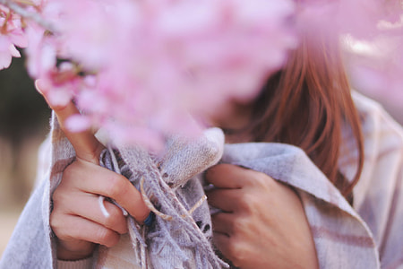 close photo of pink clustered flower behind woman wearing white and gray scarf thumbnail